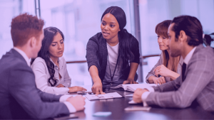 A imagem mostra uma Group Product Manager liderando uma reunião junto à equipe de Produto.