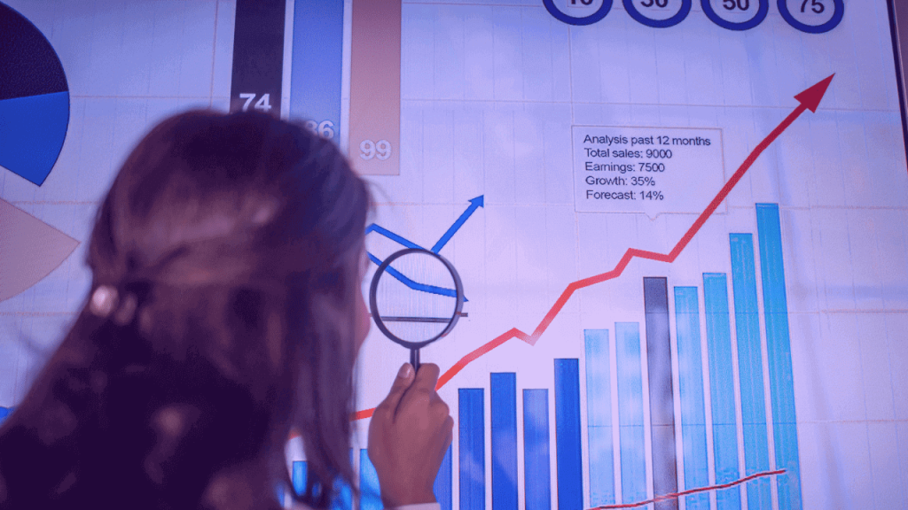 A imagem mostra uma mulher com uma lupa, observando um gráfico em crescimento. A foto sugere uma análise de dados obtidos em uma pesquisa de mercado.